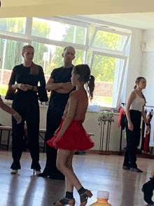 a girl in a red skirt is dancing in front of a man