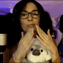 a woman wearing glasses and headphones is holding a stuffed animal