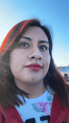 a woman with red hair is wearing a red jacket and a white shirt with the letter t on it