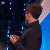 a man in a black shirt is holding a rubik 's cube in his hand