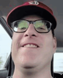 a close up of a man wearing glasses and a hat .