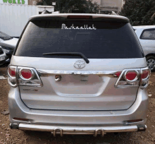 a silver toyota is parked in a gravel area