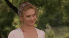 a woman wearing a white shirt and a headband smiles