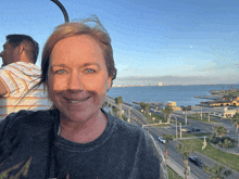 a woman in a black shirt is smiling in front of the ocean