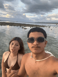 a man and a woman are posing for a picture on a beach