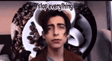 a young man is standing in front of a plate of coffee beans with the words `` stop everything '' written on it .