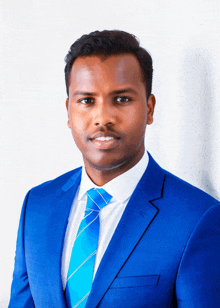 a man in a blue suit and tie is smiling for the camera