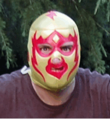 a man wearing a yellow and red mask with flames on his face