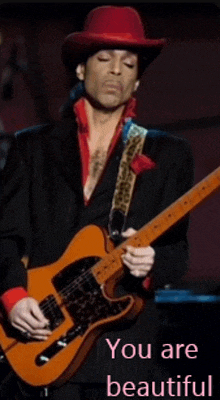 a man in a red hat is playing a guitar with the words " you are beautiful " written below him