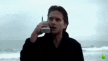 a man is talking on a cell phone on a beach .