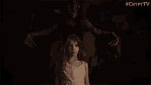 a little girl is standing in front of a monster in the dark .