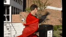 a man in a red cape is standing next to a trash can with a no smoking sign on it