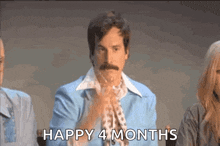 a man with a mustache is sitting at a table and says happy 4 months .