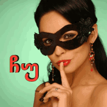 a woman wearing a black mask holds her finger to her lips in front of a sign that says by