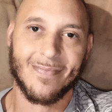 a man with a beard is smiling and wearing a gray shirt