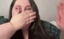 a woman is covering her mouth with her hand while laying on a bed .