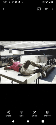 a man is laying on a table in a laundromat and the time is 9:01