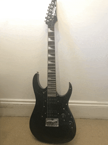 a black ibanez electric guitar is sitting on a carpeted floor