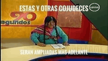 a man is sitting at a table with a book and a sign that says estas y otras cojudeces .