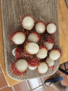 a wooden cutting board with rambutans on it