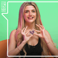 a woman is holding a heart shaped necklace in front of a green background with the word hspr on it