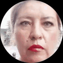 a woman with red lipstick is looking at the camera in a circle .