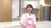 a woman wearing a pink apron that says laddy