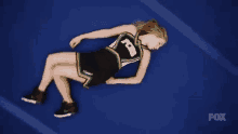 a cheerleader wearing a fox uniform is laying on the ground