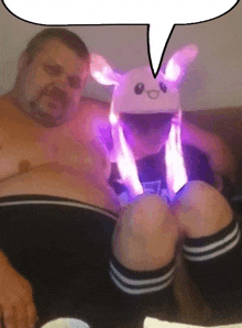 a shirtless man is sitting next to a child wearing a bunny hat and knee high socks .