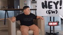 a boy sitting in a chair in front of a sign that says hey