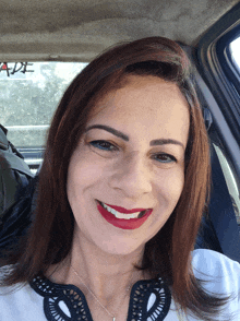 a woman is smiling in a car with a sticker on the windshield that says ade