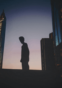 a silhouette of a man standing in front of a skyscraper