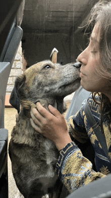 a woman is kissing a dog on the nose while sitting in a car