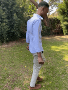 a man in a blue shirt and white pants is standing in a grassy field