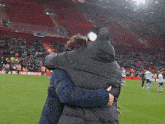 two people hugging on a soccer field with a sign in the background that says ' chinese ' on it