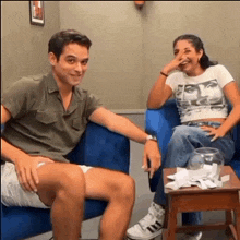 a man and a woman are sitting on a blue couch laughing