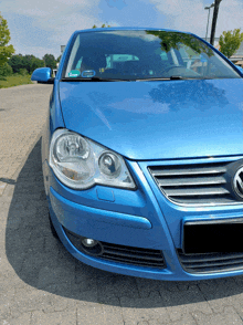 a blue volkswagen car is parked on a brick pavement