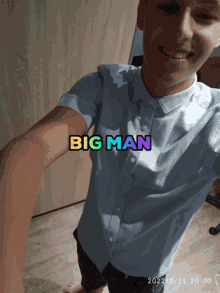 a man taking a selfie with the words big man written on his shirt