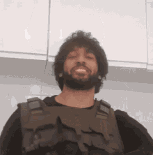 a man with a beard wearing a tactical vest smiles for the camera