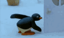 a cartoon penguin is walking in the snow next to a building .