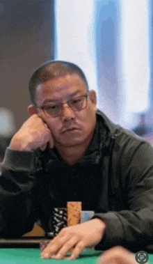 a man with glasses sits at a poker table