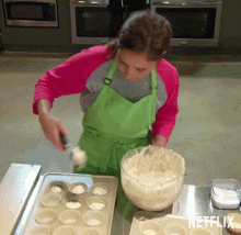 a woman in a green apron is making cupcakes in front of a tray that says netflix on the bottom