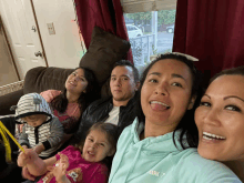 a woman wearing a light blue hoodie with the word mark on it poses with her family