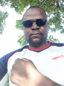 a man wearing sunglasses and a black and white shirt has his fist up in the air