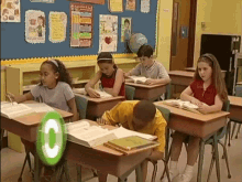 a group of children sit at their desks in a classroom with a green circle that says c on it