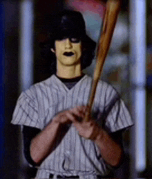 a man in a baseball uniform is holding a bat in his hand .