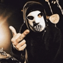 a man wearing a hooded mask is giving the middle finger .