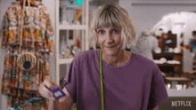 a woman in a purple shirt is standing in front of a sign for netflix