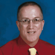 a man wearing glasses and a red shirt and yellow tie