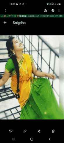 a phone screen shows a woman in a yellow and green dress and the name snigdha